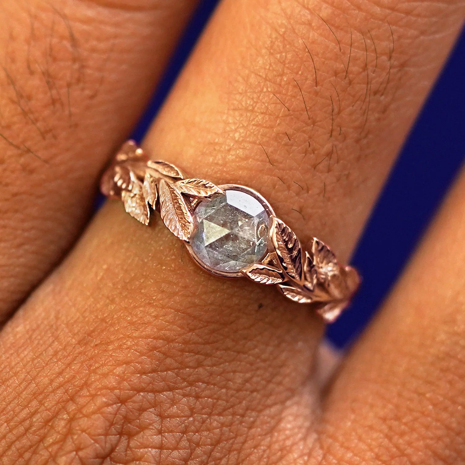 Close up view of a model's fingers wearing a 14k rose gold Diamond Leaves Ring