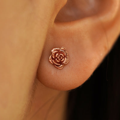 Close up view of a model's ear wearing a 14k rose gold Rose Earring