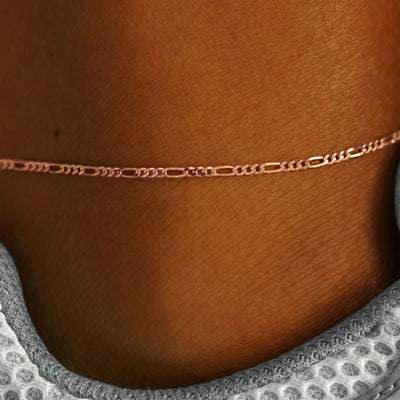 Close up view of a model's ankle wearing a rose gold Figaro Anklet