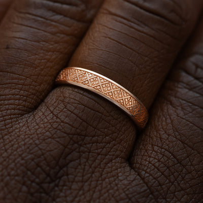 Close up view of a model wearing a solid 14k rose gold diamond patterned band