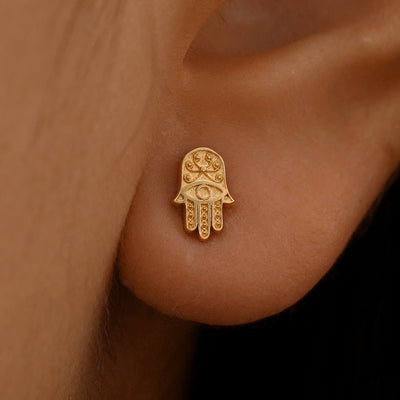 Close up view of a model's ear wearing a 14k rose gold Hamsa Earring