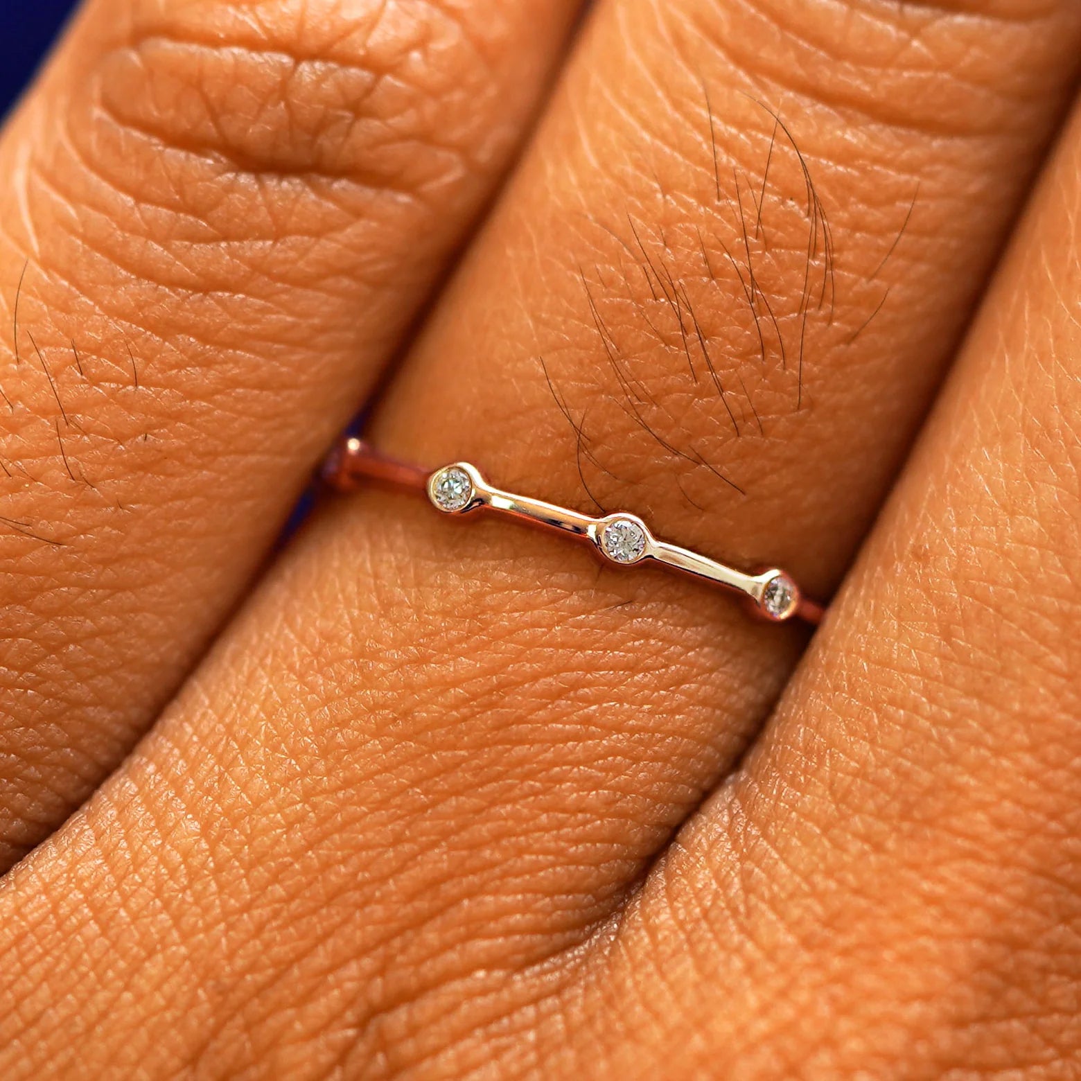Close up view of a model's fingers wearing a 14k rose gold Spaced Infinity Ring