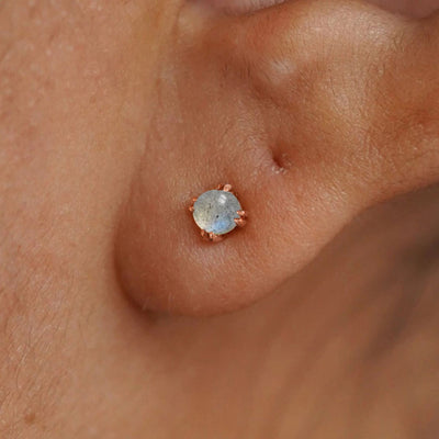 Close up view of a model's ear wearing a rose gold labradorite earring