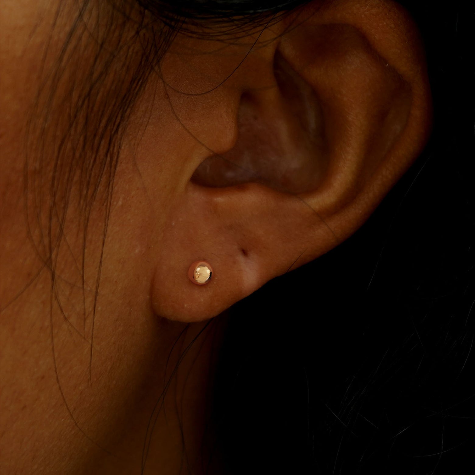 Close up view of a model's ear wearing a rose gold Medium Ball Earring