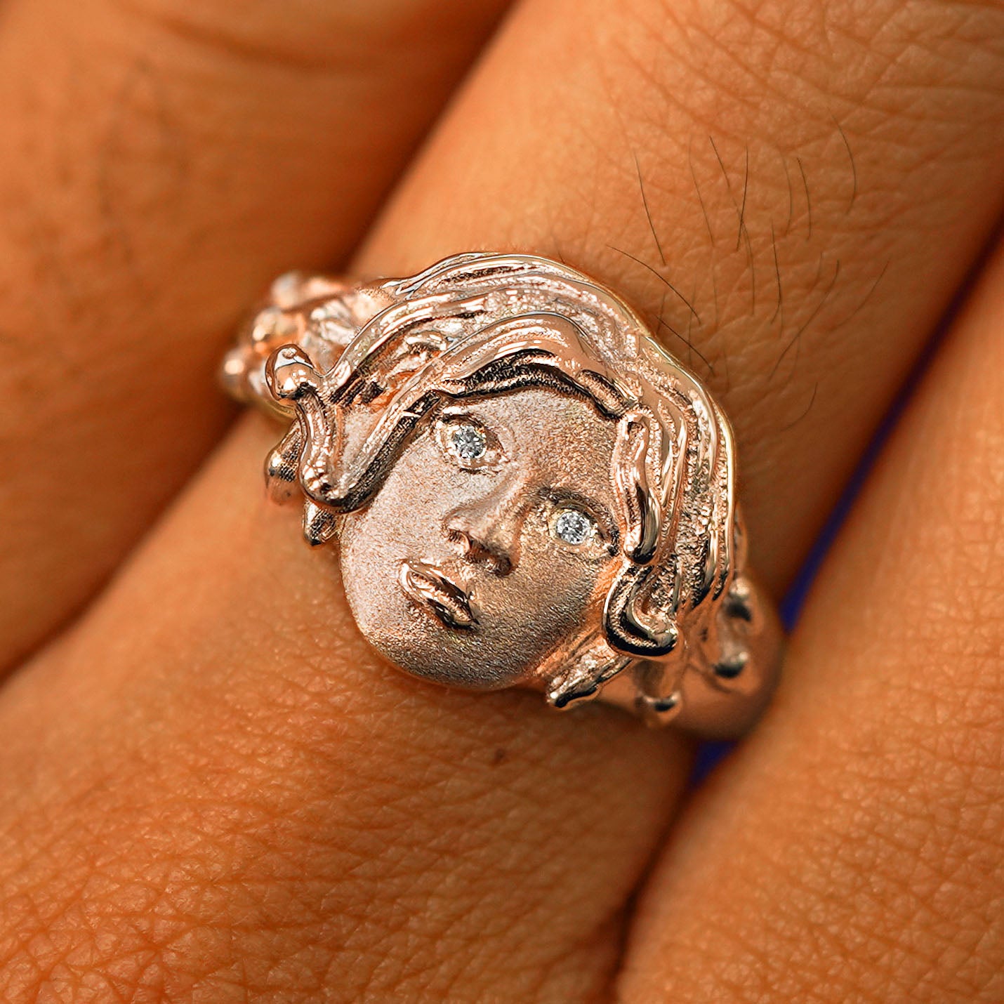Close up view of a model's fingers wearing a 14k rose gold Medusa Ring