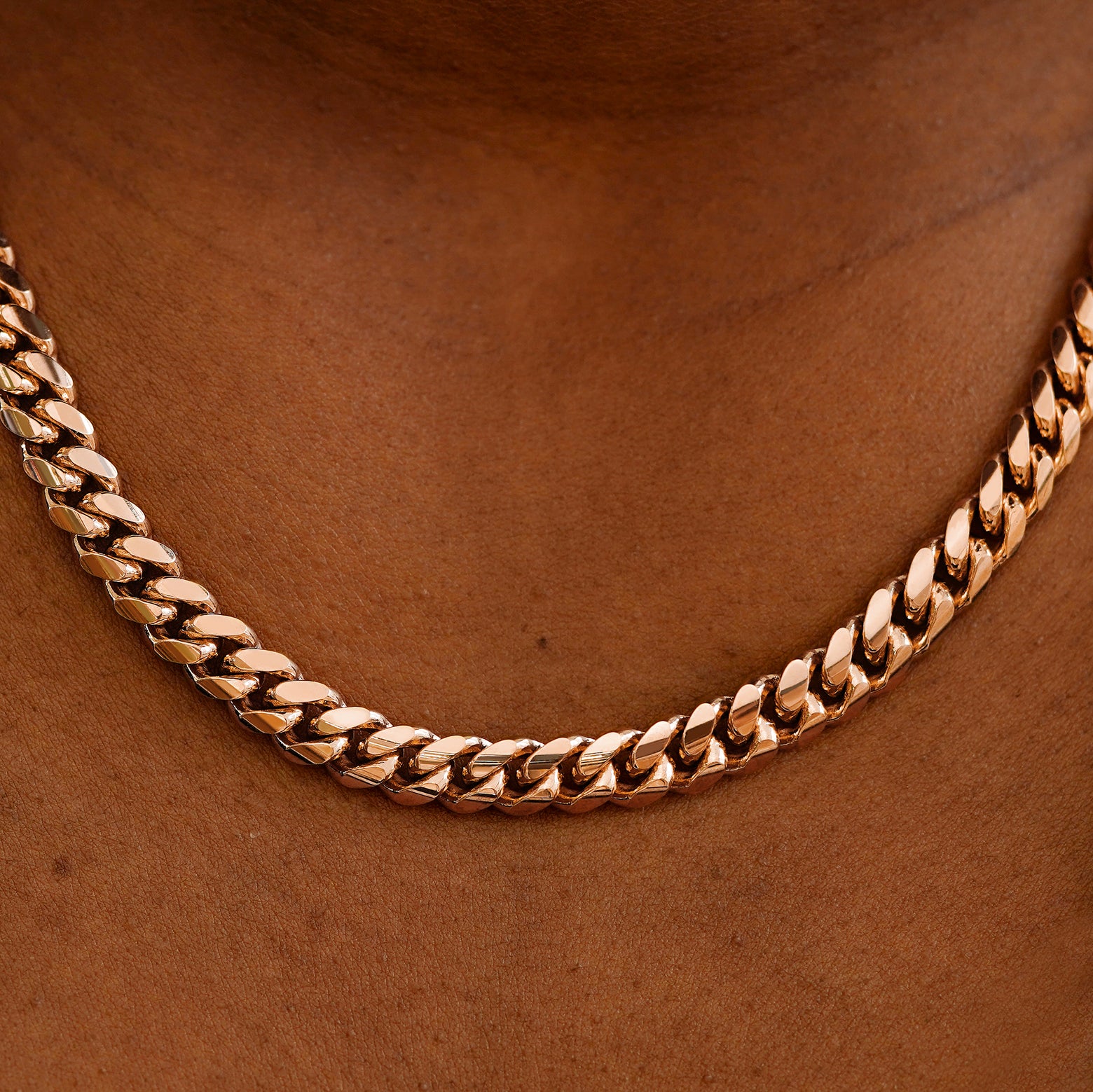 Close up view of a model's neck wearing a rose gold Miami Cuban Chain