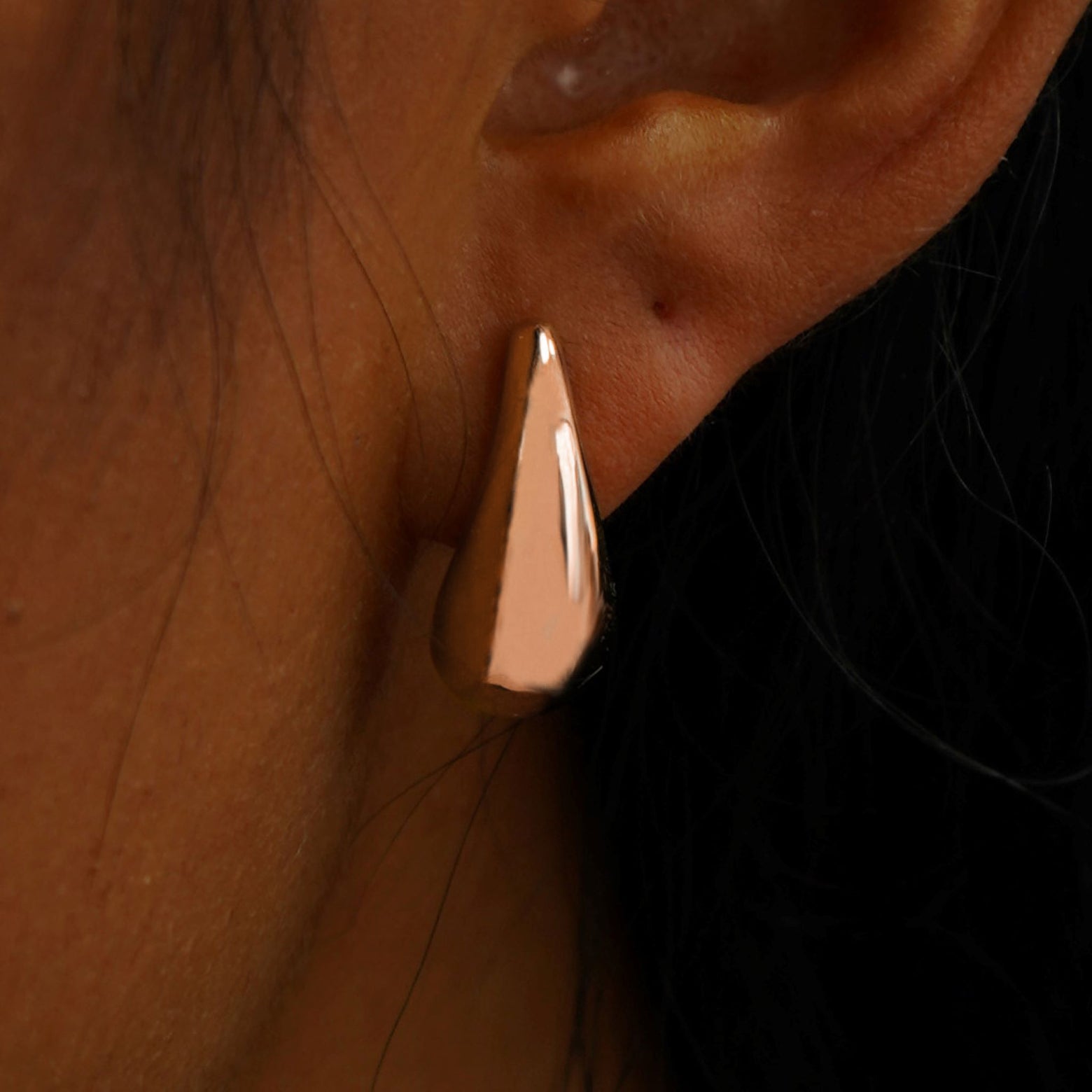 Close up view of a model's ear wearing a rose gold black 5mm Moissanite Earring
