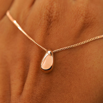 A model's holding a rose gold Puffy Teardrop Necklace across the back of their hand