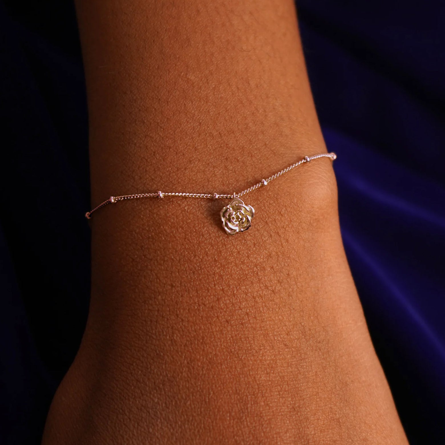 Close up view of a model's wrist wearing a rose gold Rose Charm on a Beaded Essential Chain