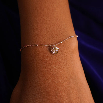 Close up view of a model's wrist wearing a rose gold Rose Charm on a Beaded Essential Chain
