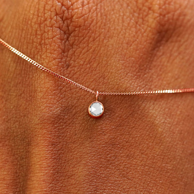 Close up view of a 14k rose gold Rose Cut Diamond Necklace draped across the back of a model's hand