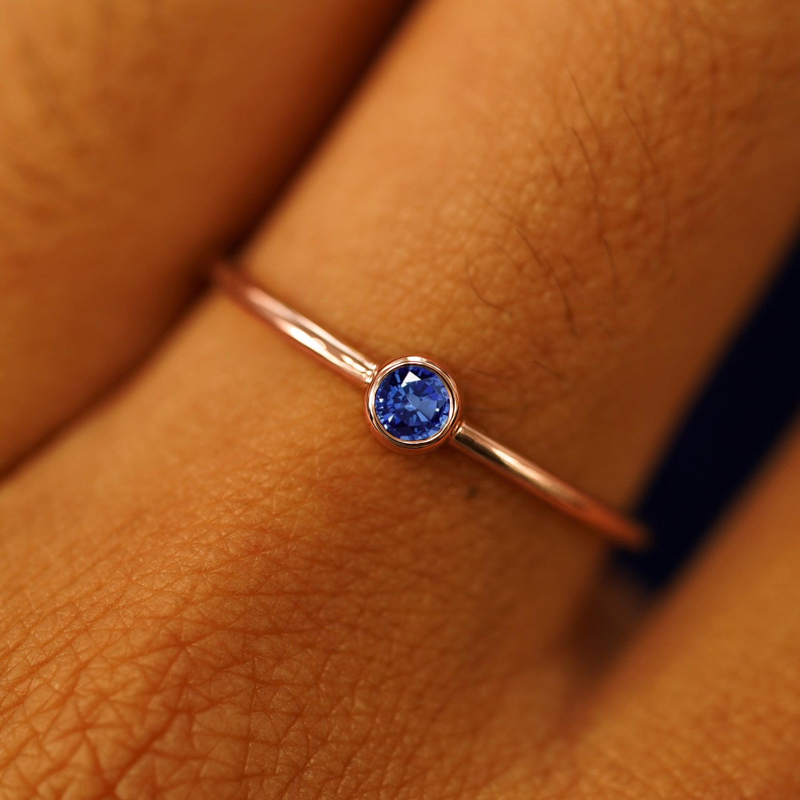 Close up view of a model's fingers wearing a 14k rose gold Sapphire Ring