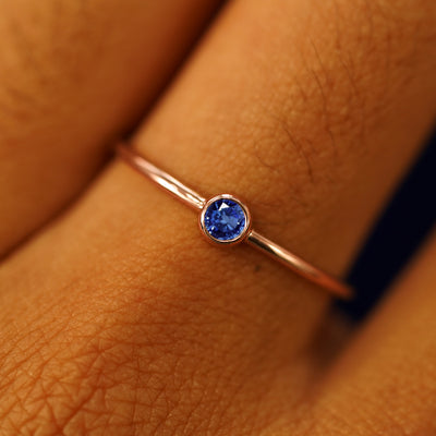 Close up view of a model's fingers wearing a 14k rose gold Sapphire Ring