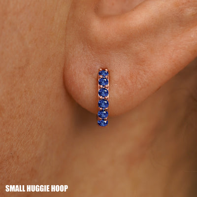 Close up view of a model's ear wearing a rose gold Small Blue Sapphire Huggie Hoop