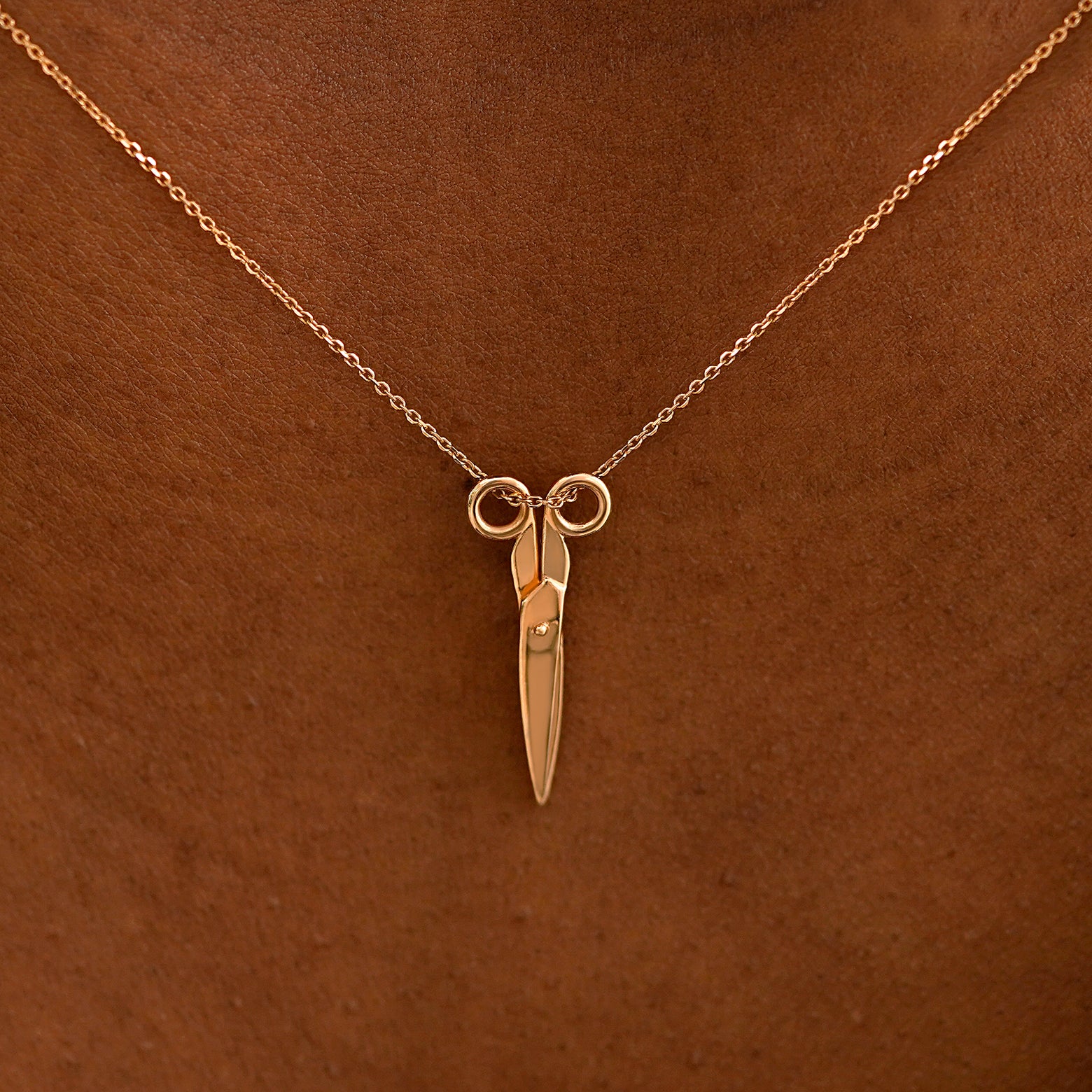 Close up view of a model's neck wearing a solid 14k rose gold Scissors Necklace