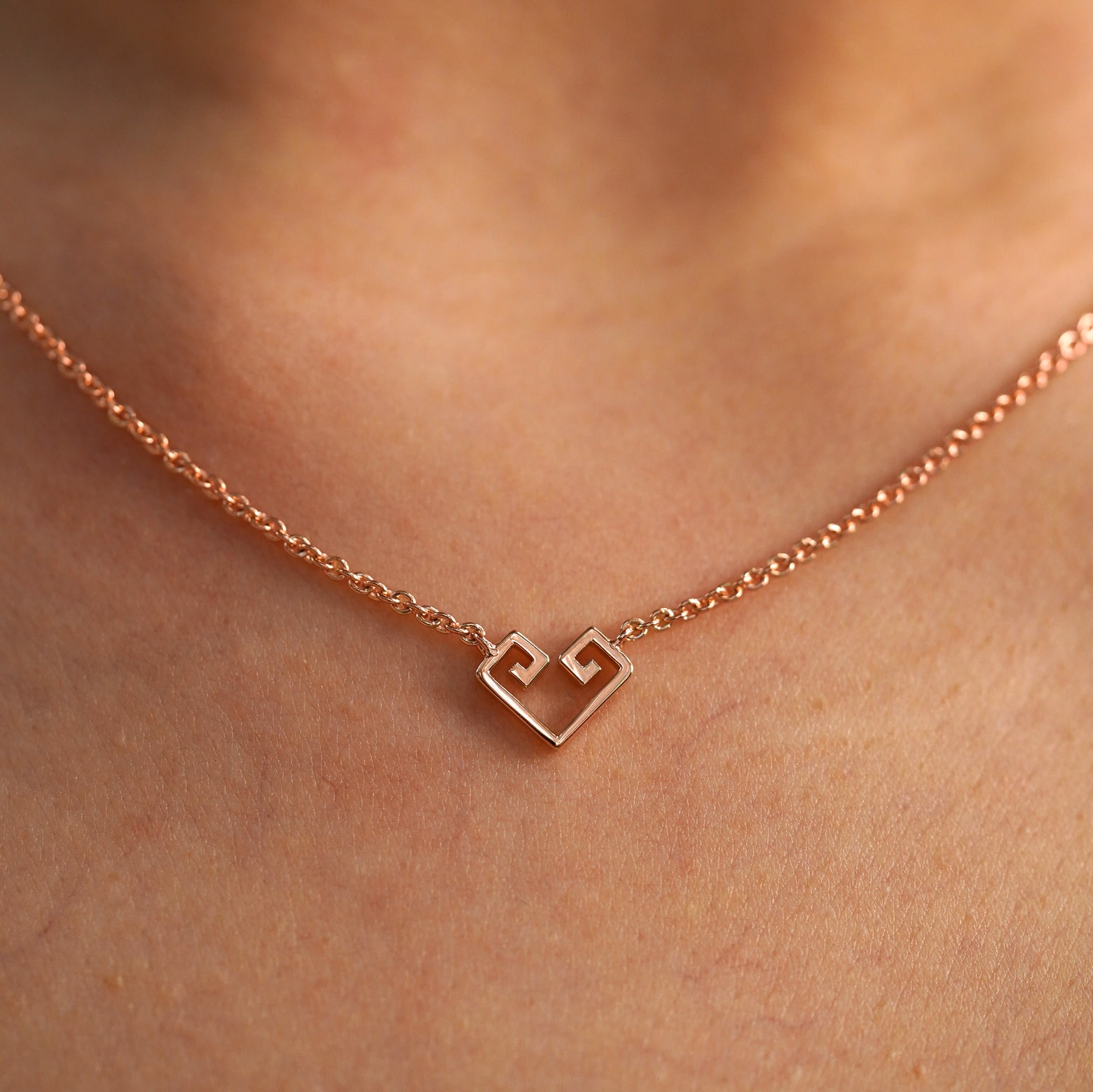 A close up view of a model's neck wearing a rose gold Small Chere Heart Necklace