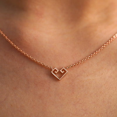 A close up view of a model's neck wearing a rose gold Small Chere Heart Necklace