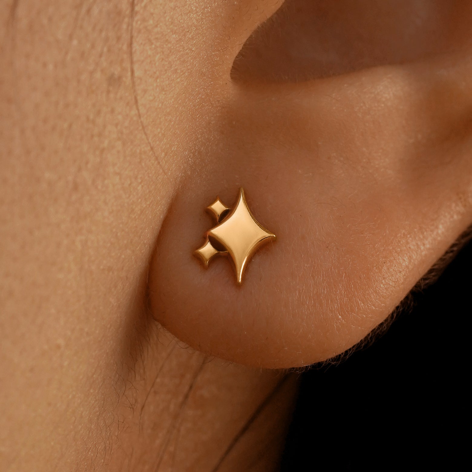 Close up view of a model's ear wearing a 14k rose gold Sparkly Emoji Earring