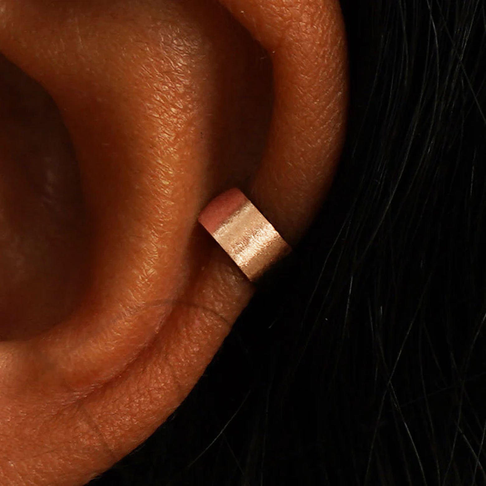 Close up view of a model's ear wearing a 14k rose gold Stardust Thick Cuff