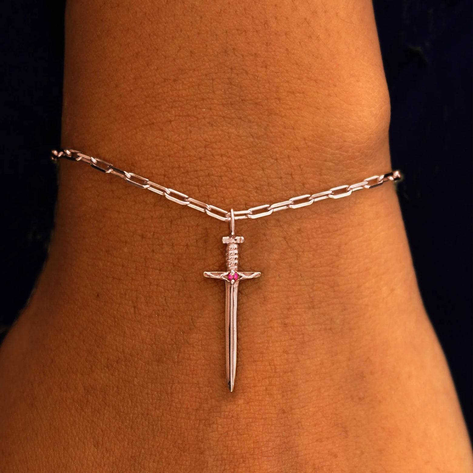 Close up view of a model's wrist wearing a rose gold Sword Charm on a Butch Chain Bracelet