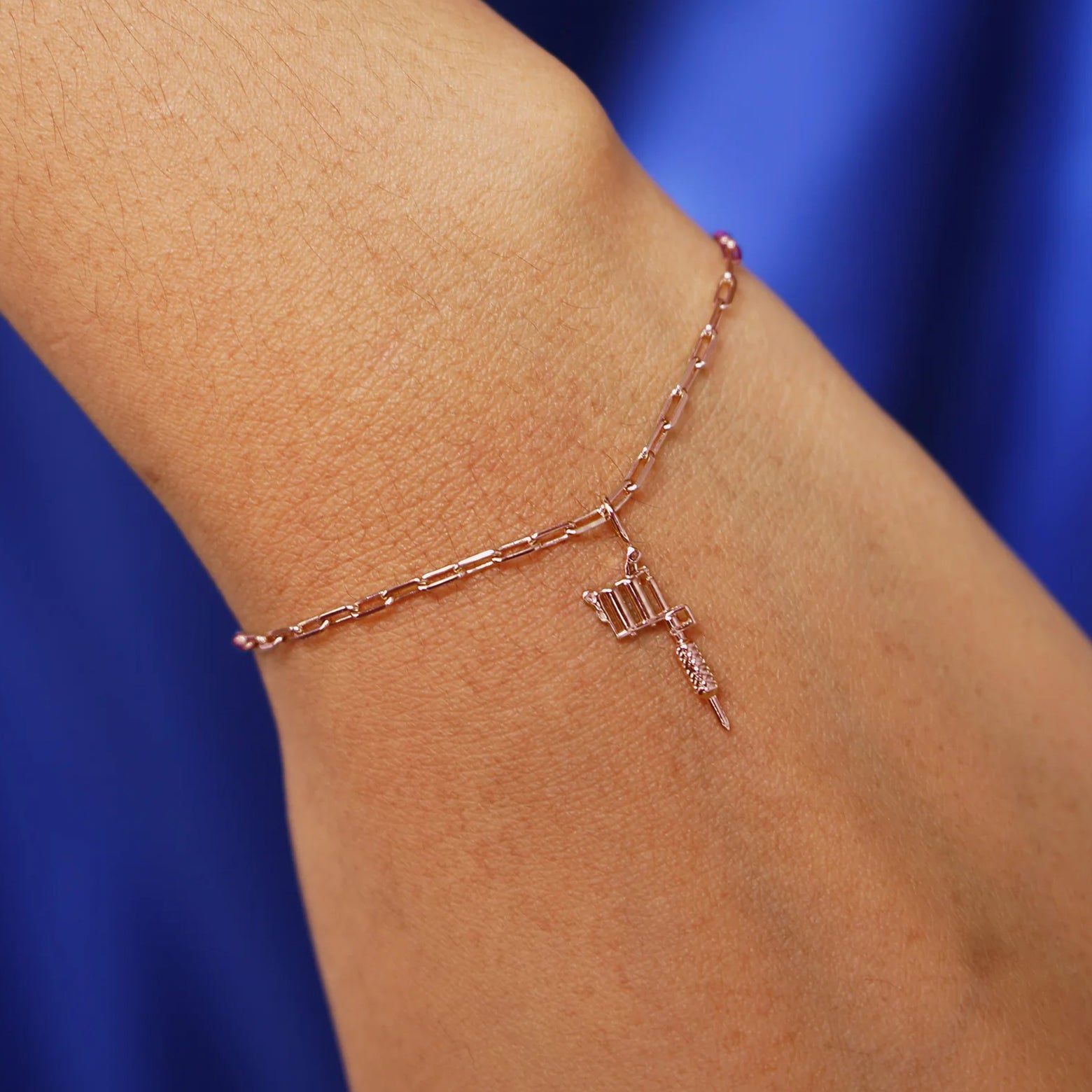 Close up view of a model's wrist wearing a rose gold Tattoo Machine Charm on a Butch Bracelet