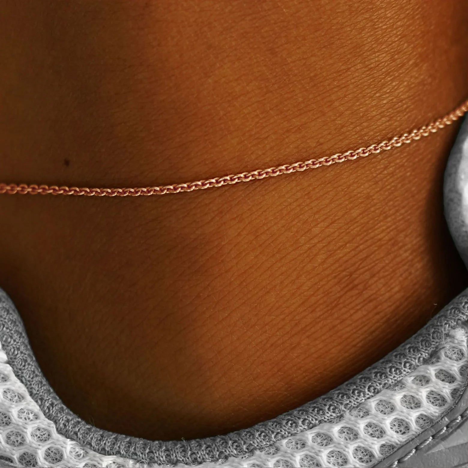 Close up view of a model's ankle wearing a rose gold Thick Cable Anklet