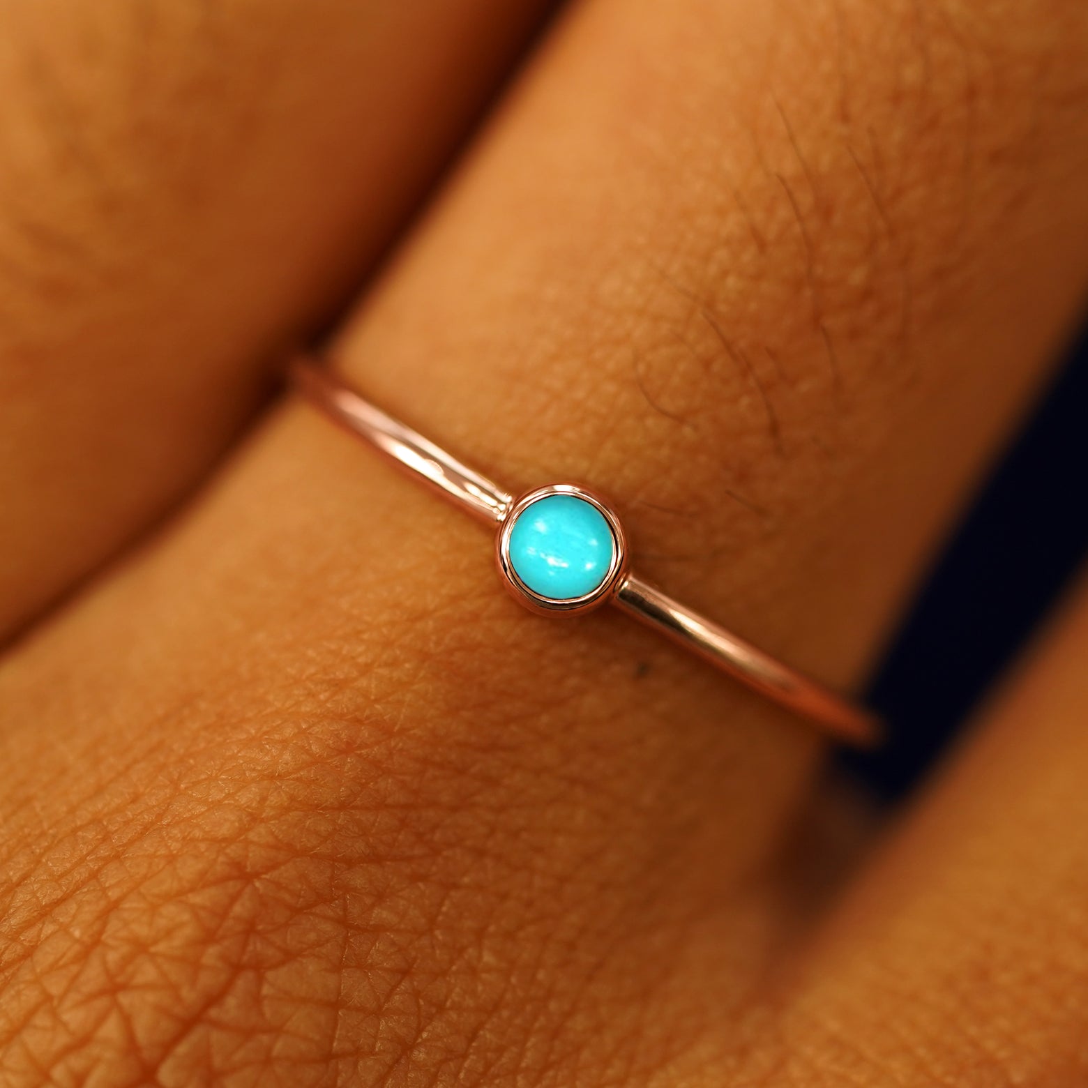 Close up view of a model's fingers wearing a 14k rose gold Turquoise Ring