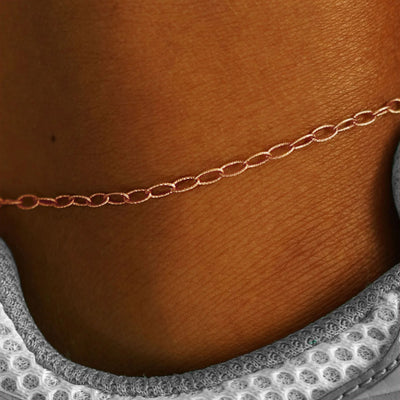 Close up view of a model's ankle wearing a solid rose gold Veren Anklet