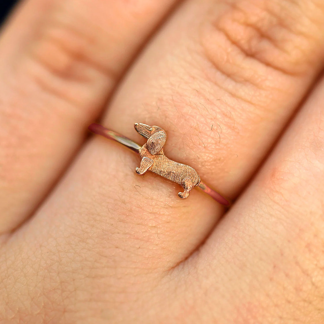 Close up view of a model's fingers wearing a 14k rose gold Dog Ring