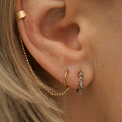 A model wearing a rose cut Salt and Pepper Diamond Huggie Hoop with a Thick Cuff with Chain and Mini Seamless Huggie Hoop