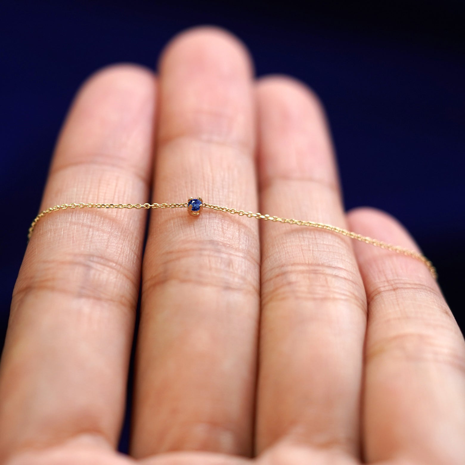 A yellow gold sapphire Gemstone Cable Necklace resting on a model's fingers