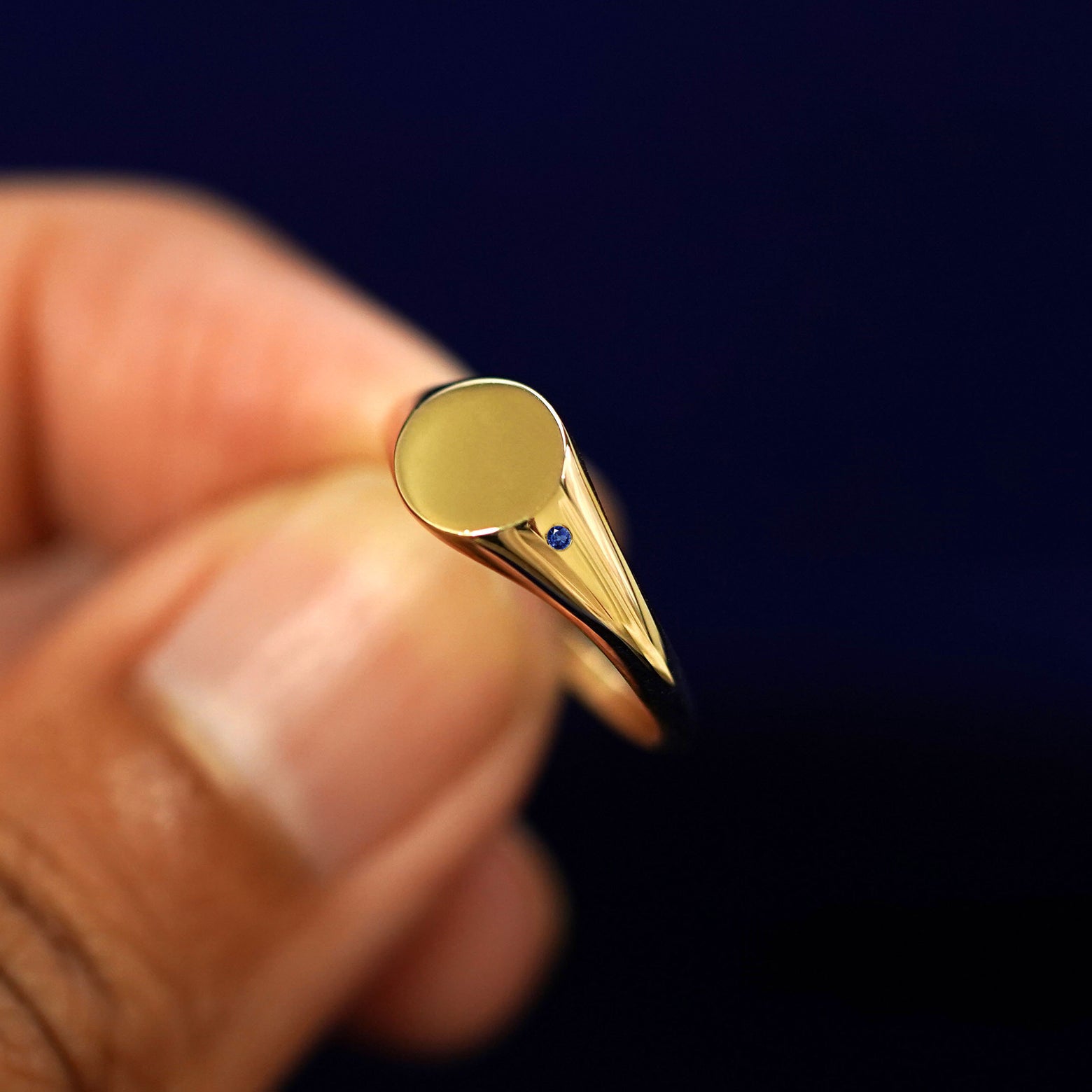 A model holding a sapphire Gemstone Signet Ring tilted to show the side of the ring