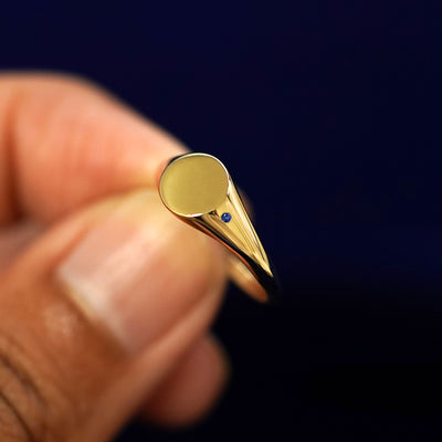 A model holding a sapphire Gemstone Signet Ring tilted to show the side of the ring