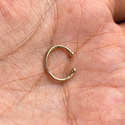 Alternate view of a solid 14 karat yellow gold Shimmer Line Cuff earring resting on a model's palm