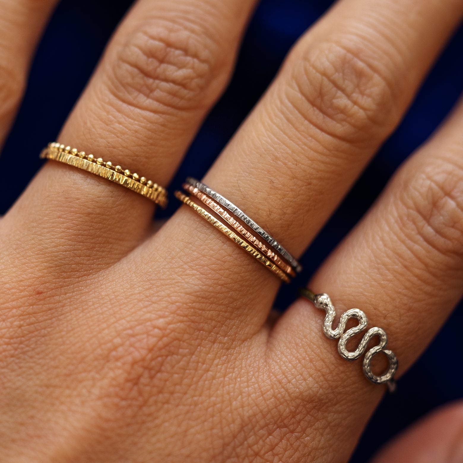 Close up view of a model's fingers wearing a 14k yellow, white, rose and champagne gold Shimmer Ring