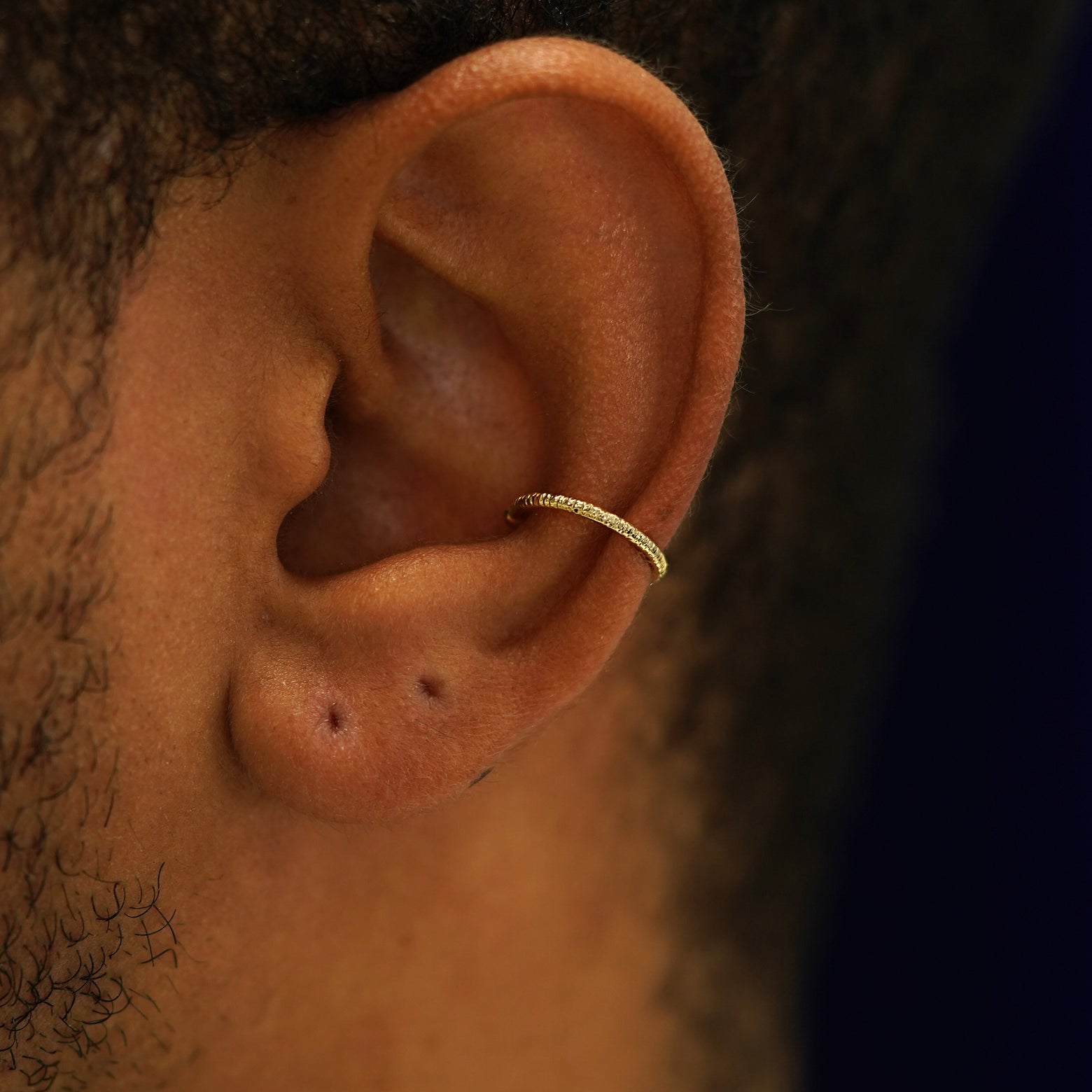 A model's ear wearing a 14k yellow gold Shimmer Line Cuff