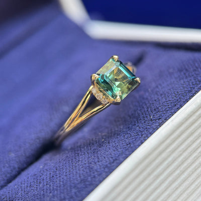 side view of 14k yellow gold and 1.08ct Asscher Teal Sapphire with 6 clear diamonds on tapered band custom ring size 5.25