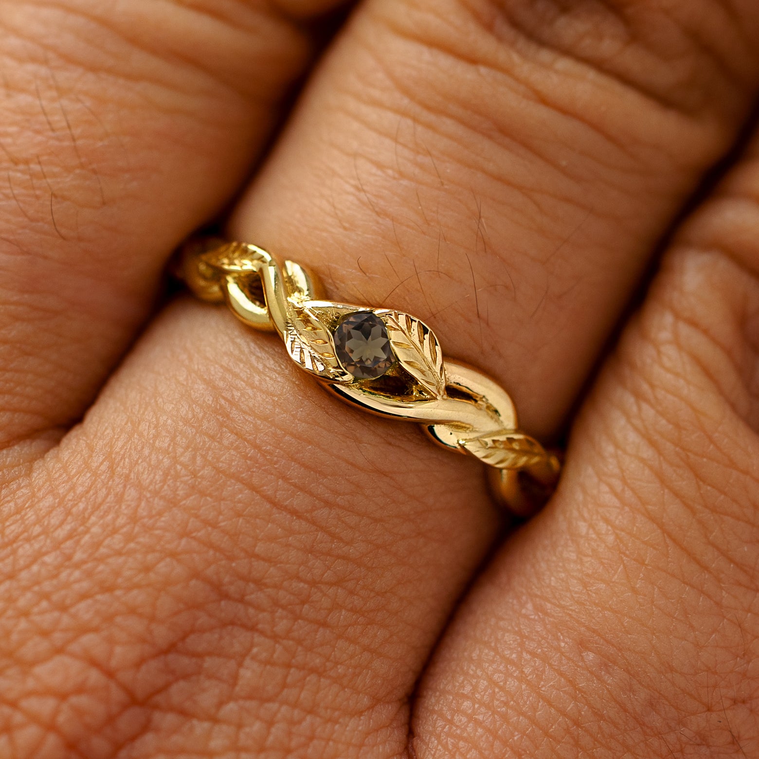 A solid 14k yellow gold smoky quartz leaves and vines ring on a model's finger