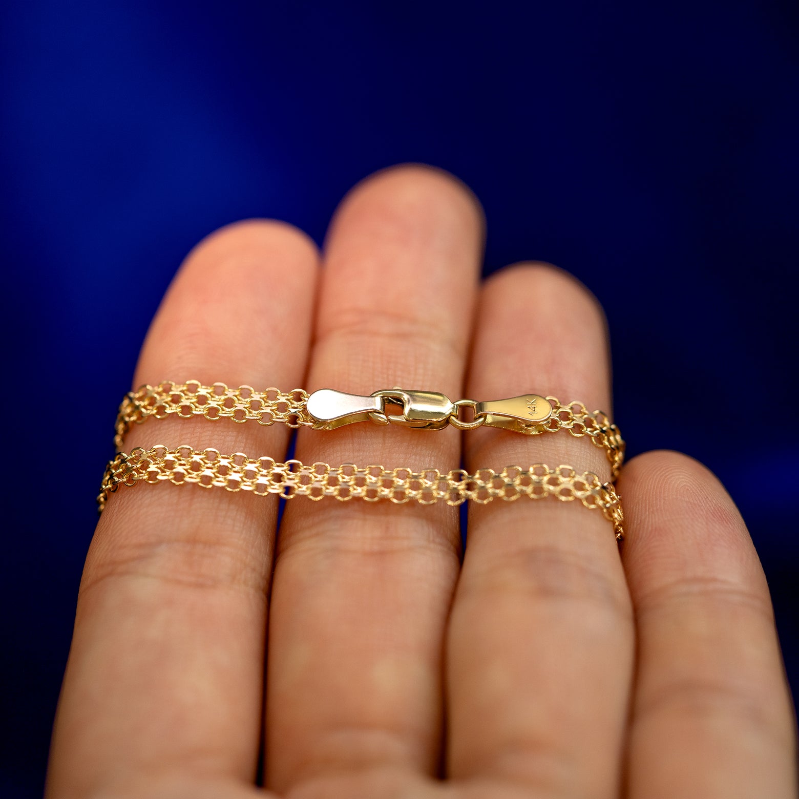 A yellow gold Bismarck Chain Anklet wrapped around a model's fingers to show the chain and the lobster claw clasp