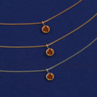 Three versions of the Citrine Necklace shown in options of yellow, white and rose gold on a dark blue background