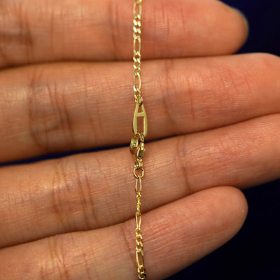 A lobster lock with an AU Automic Gold Plate on a solid gold Figaro Chain