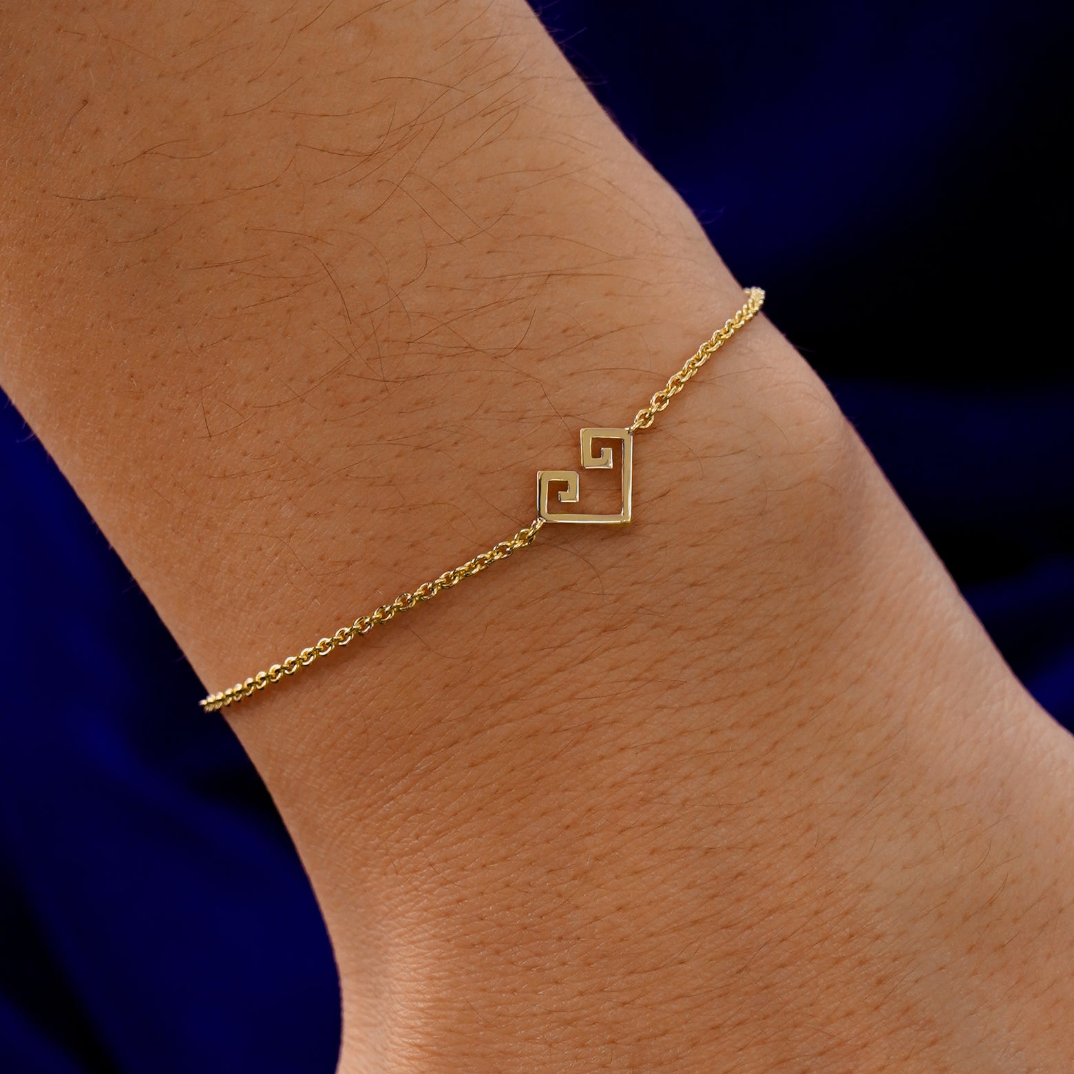 A model's wrist wearing a 14k solid gold Chere Heart Bracelet