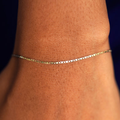 Close up view of a model's wrist wearing a solid yellow gold Valentine Bracelet