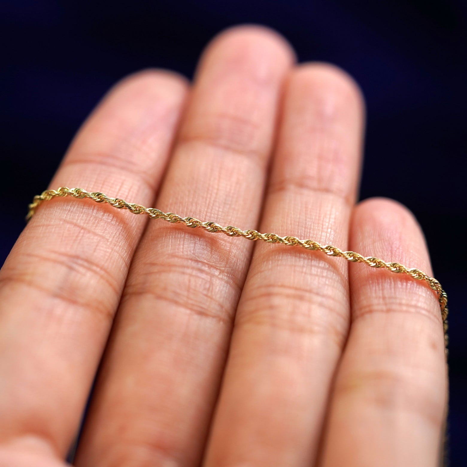 A yellow gold Rope Bracelet resting on a model's fingers