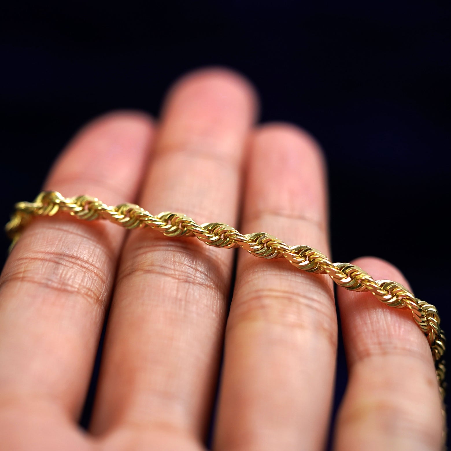 A yellow gold Thick Rope Bracelet resting on a model's fingers