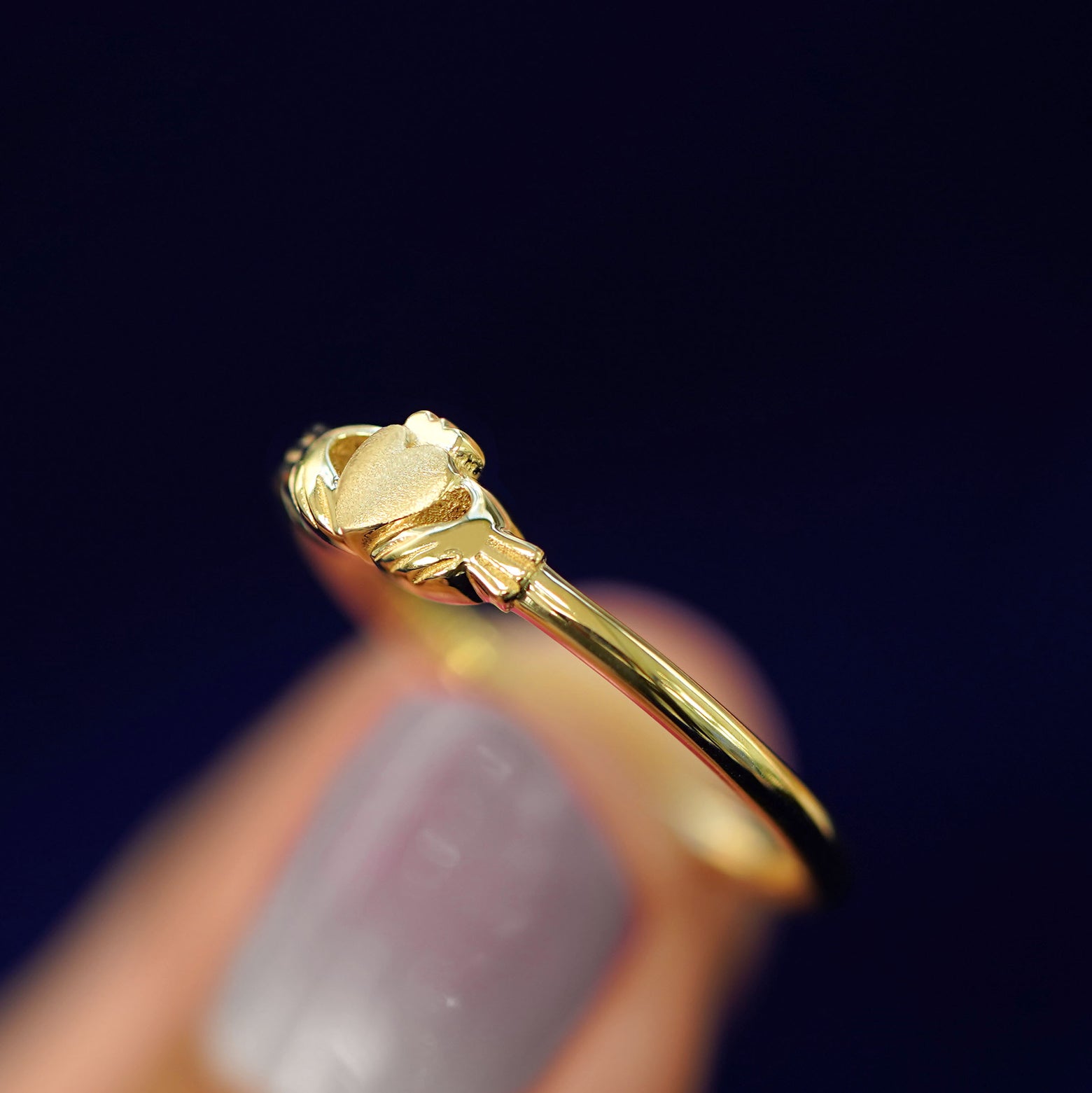 A model holding a Thin Claddagh Ring tilted to show the side of the ring