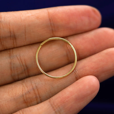 A yellow gold Bar Ring in a model's hand showing the thickness of the band