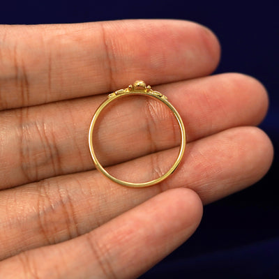 A yellow gold Curvy Bee Ring in a model's hand showing the thickness of the band