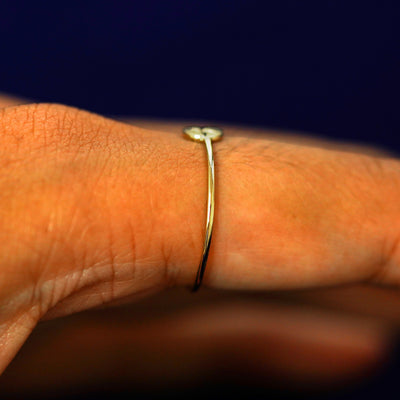 Side view of a models finger wearing a star disk ring o show the ring height