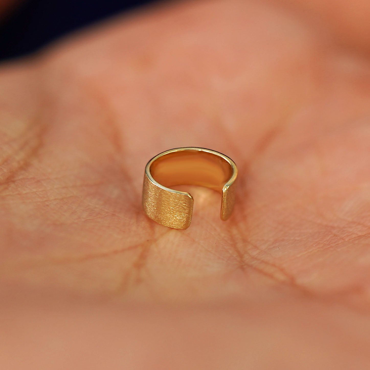 A solid yellow gold Thick Stardust Cuff earring resting in a model's palm to show detials of the finish